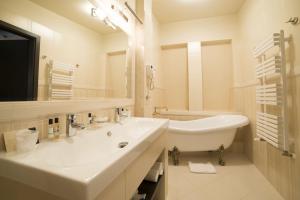 a white bathroom with a sink and a bath tub at Hotel Starka in Opole