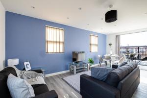 a living room with a couch and a blue wall at Top Floor Apartment with Private Balcony in Stockport Centre by HASS HAUS in Stockport