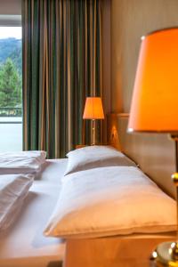 a bedroom with a bed with a lamp and a window at Hotel Brenner - Stop & Go in Vipiteno