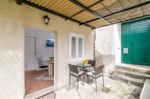 patio con mesa, sillas y puerta verde en Apartment and Room Kapelica, en Dubrovnik
