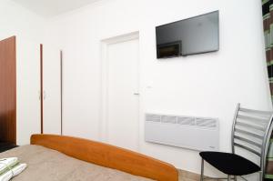 1 dormitorio con 1 cama y TV en la pared en Apartment and Room Kapelica, en Dubrovnik