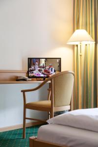 Habitación de hotel con escritorio con silla y TV. en Hotel Brenner - Stop & Go, en Vipiteno