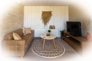 ein Wohnzimmer mit einem Sofa und einem Tisch in der Unterkunft Wellness Lodge aan de Braassem in Rijnsaterwoude