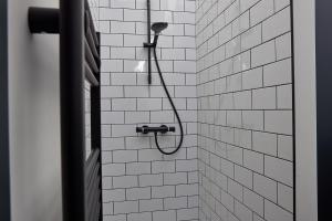 Una ducha con cabezal de ducha en un baño de azulejos blancos. en No 6 at Simpson Street Apartments Sunderland, en Sunderland