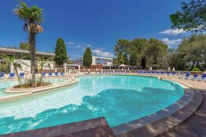 a large swimming pool with chairs and a palm tree at Belambra Clubs Le Pradet - Lou Pigno in Le Pradet
