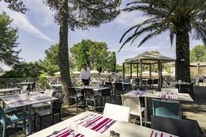 a restaurant with tables and chairs and palm trees at Belambra Clubs Le Pradet - Lou Pigno in Le Pradet
