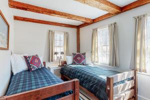 two beds in a room with two windows at Vermont Mountain Farmhouse in Ludlow