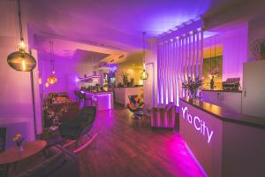 Cette chambre violette comprend un bar avec des chaises et une table. dans l'établissement Hotel via City Leipzig Mitte, à Leipzig