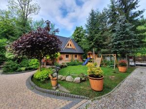 a house with a garden with potted plants in front of it at Domek Góralski Chatka Puchatka in Poronin