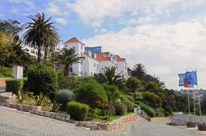 a large white house on a hill with palm trees at INATEL Foz Do Arelho in Foz do Arelho