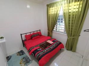 a bedroom with a red bed and a window at Nawra Homestay Besut - Free Wifi in Kampung Raja