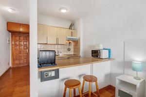una cocina con 2 taburetes y una barra con microondas en Garden City, en Costa de Adeje
