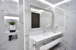 a white bathroom with a sink and a mirror at Bourbon Boutique Hotel in Yerevan
