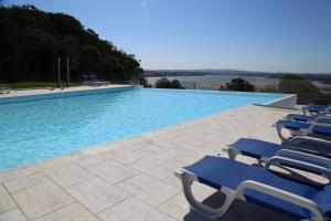 uma piscina com espreguiçadeiras azuis num pátio em INATEL Foz Do Arelho na Foz do Arelho