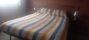 a bed with a striped comforter in a bedroom at crimdon dene holiday park in Hartlepool