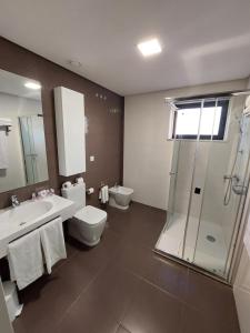 a bathroom with a toilet and a sink and a shower at Hotel Monte Lírio in Espinho