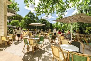 un patio avec des tables, des chaises et des parasols dans l'établissement Belambra Clubs L'Isle Sur La Sorgue - Domaine De Mousquety, à LʼIsle-sur-la-Sorgue