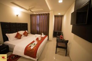 a bedroom with a bed and a chair and a television at ROYAL ROSETTE LAKE VIEW Bhimtal in Nainital