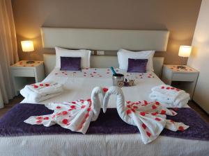 a bedroom with a bed with two towels and two lamps at Hotel Monte Lírio in Espinho