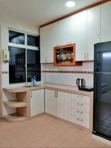 a kitchen with white cabinets and a black refrigerator at Bukit Indah Nearby Aeon Issix 4 rooms up to 8 pax in Johor Bahru