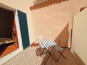 una mesa y dos sillas sentadas junto a una pared en Aba Maya Alghero en Alguer