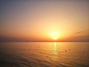 a sunset over the ocean with people in the water at Appartamento relax con giardino in Caria
