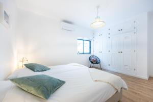 a white bedroom with a bed with green pillows at Fortaleza sea view Villa Miramar - Downstairs Apartment II in Burgau
