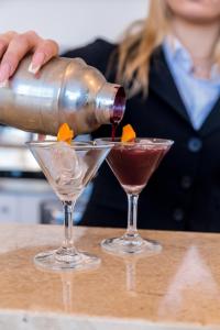 a woman is pouring a drink into two glasses at EUROPA Hotel in Vasto