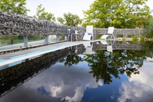 a swimming pool with chairs and a reflection in the water at Landhotel Am Rothenberg in Uslar