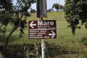 um sinal num poste com setas numa rua em Villa Aurea em Ispica