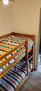 a wooden bunk bed with a colorful striped comforter at Joli T2 + coin montagne + Garage in Briançon