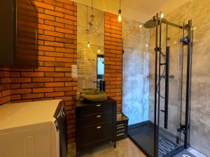 a bathroom with a shower and a brick wall at Apartament Przystań in Mechelinki