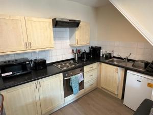 une cuisine avec des placards en bois et des comptoirs noirs dans l'établissement Cottage on the Solway Coast, à Port Carlisle