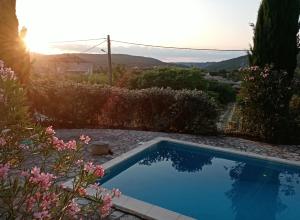 una piscina en un jardín con puesta de sol en Gîte passiflore, en Frigoulet