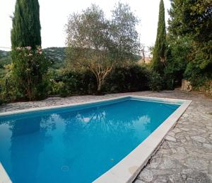 una piscina azul en un patio con árboles en Gîte passiflore, en Frigoulet