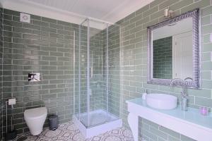 un bagno piastrellato verde con lavandino e doccia di Casa D'Alice a Vouzela