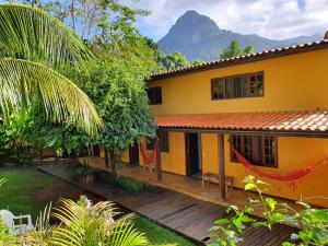 une maison jaune avec une terrasse en bois et une montagne dans l'établissement Pousada e Hostel Holandês, à Abraão