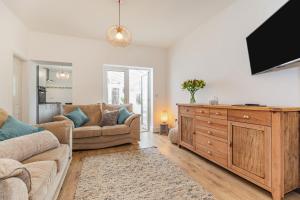 a living room with a couch and a tv at Postman's Cottage in Bridlington
