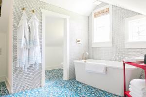 a bathroom with a white tub and a blue tile floor at The Frenchie in Round Top