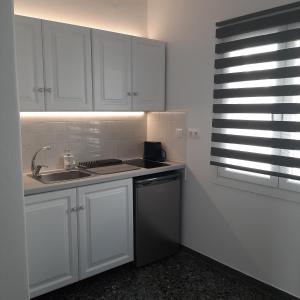 a kitchen with white cabinets and a sink and a window at Flora Rooms & Apartments in Naousa