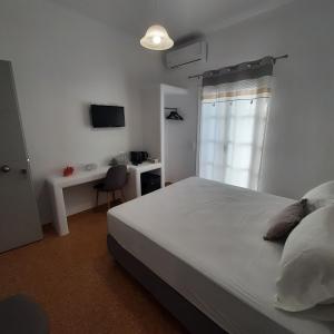 a bedroom with a bed and a desk and a window at Flora Rooms & Apartments in Naousa