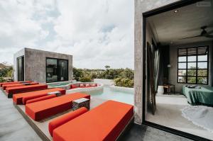 a group of red benches sitting on a patio with a pool at Kings Mansion for 26 guests! in Tulum