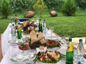 uma mesa com pratos de comida e garrafas de vinho em Finca Idoize Camping Hotel em Akhmeta