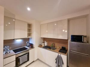 a kitchen with white cabinets and a stainless steel refrigerator at BW Arcadia deluxe apartments in Sajmište