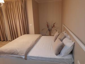 una camera da letto con letto, lenzuola e cuscini bianchi di Monte grego a Slava Rusă