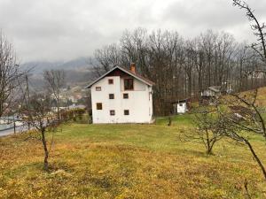 a white house on top of a grassy hill at Porodicna kuca za odmor Kovaci in Zavidovići +8 photos