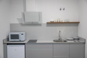 eine weiße Küche mit Mikrowelle und Spüle in der Unterkunft PALACIO REAL HOSTEL in León