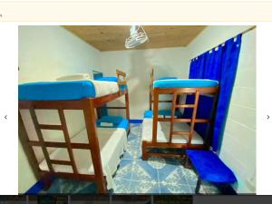 two bunk beds in a room with blue curtains at HOSTAL EL DESCANSO in Capurganá