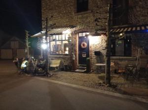 een groep mensen die 's nachts buiten een gebouw zitten bij L'ancienne Boulangerie in Durbuy