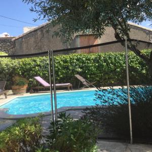 uma piscina com uma pérgula ao lado de uma casa em LE PETIT CLOS em Fontjoncouse